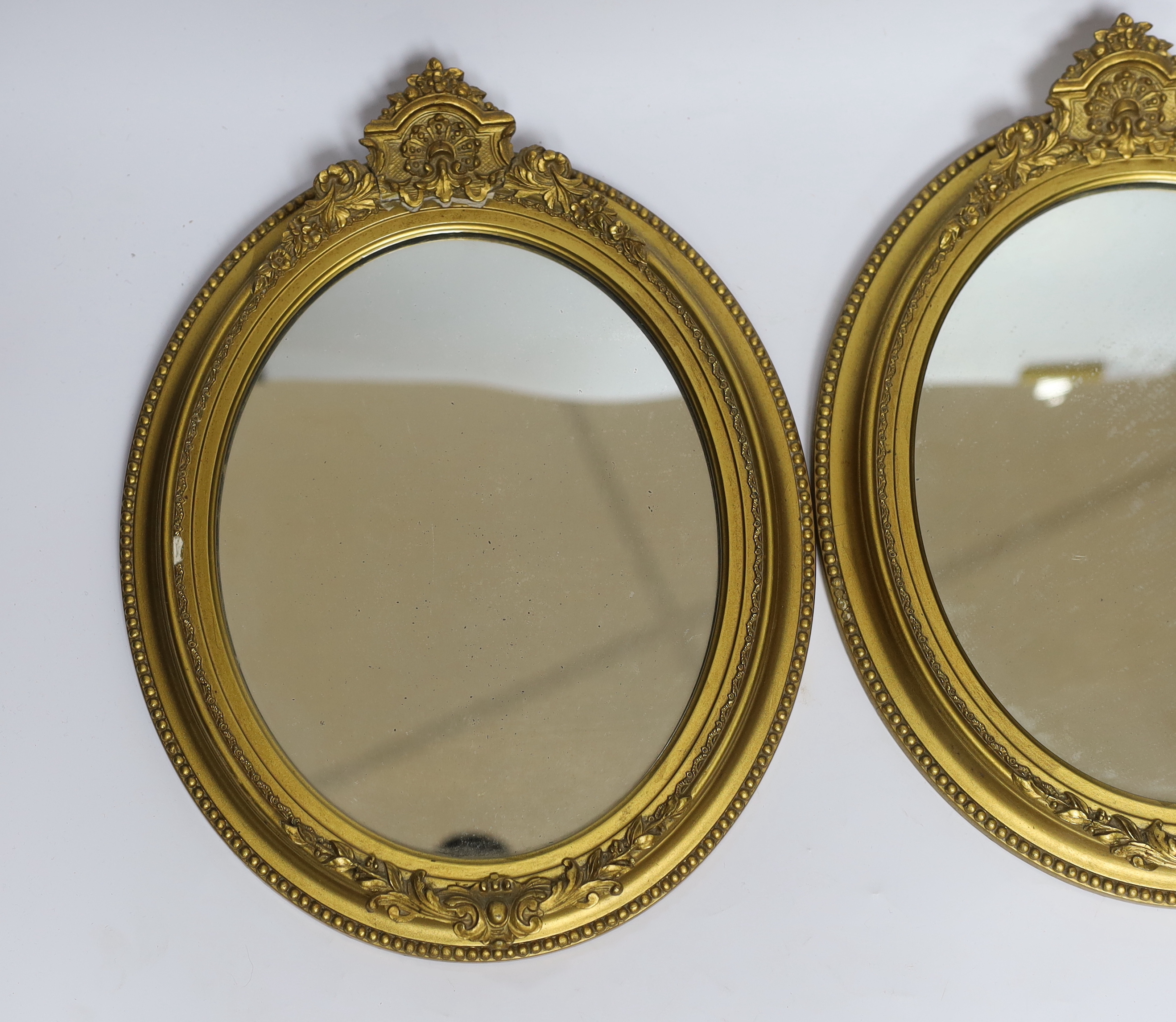 A pair of small oval giltwood and composition wall mirrors, 35cm high